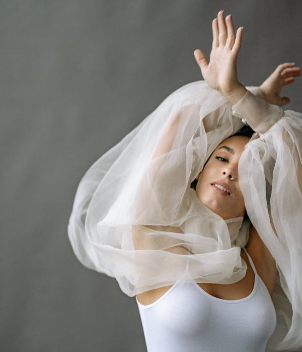 Woman in activewear performing a light, flowing movement in a minimalist studio.